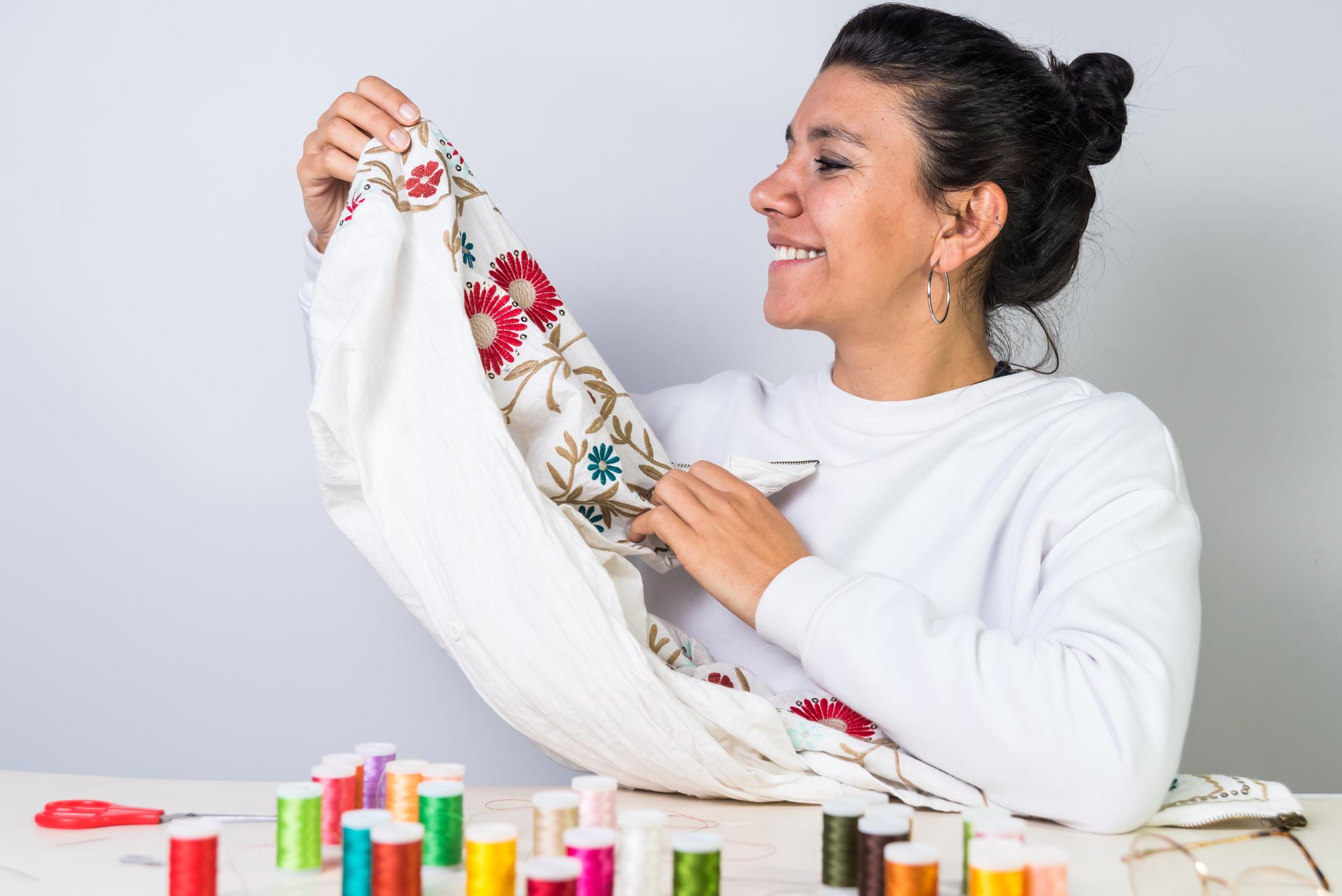 Woman embroidering a neon geometric pattern on dark fabric